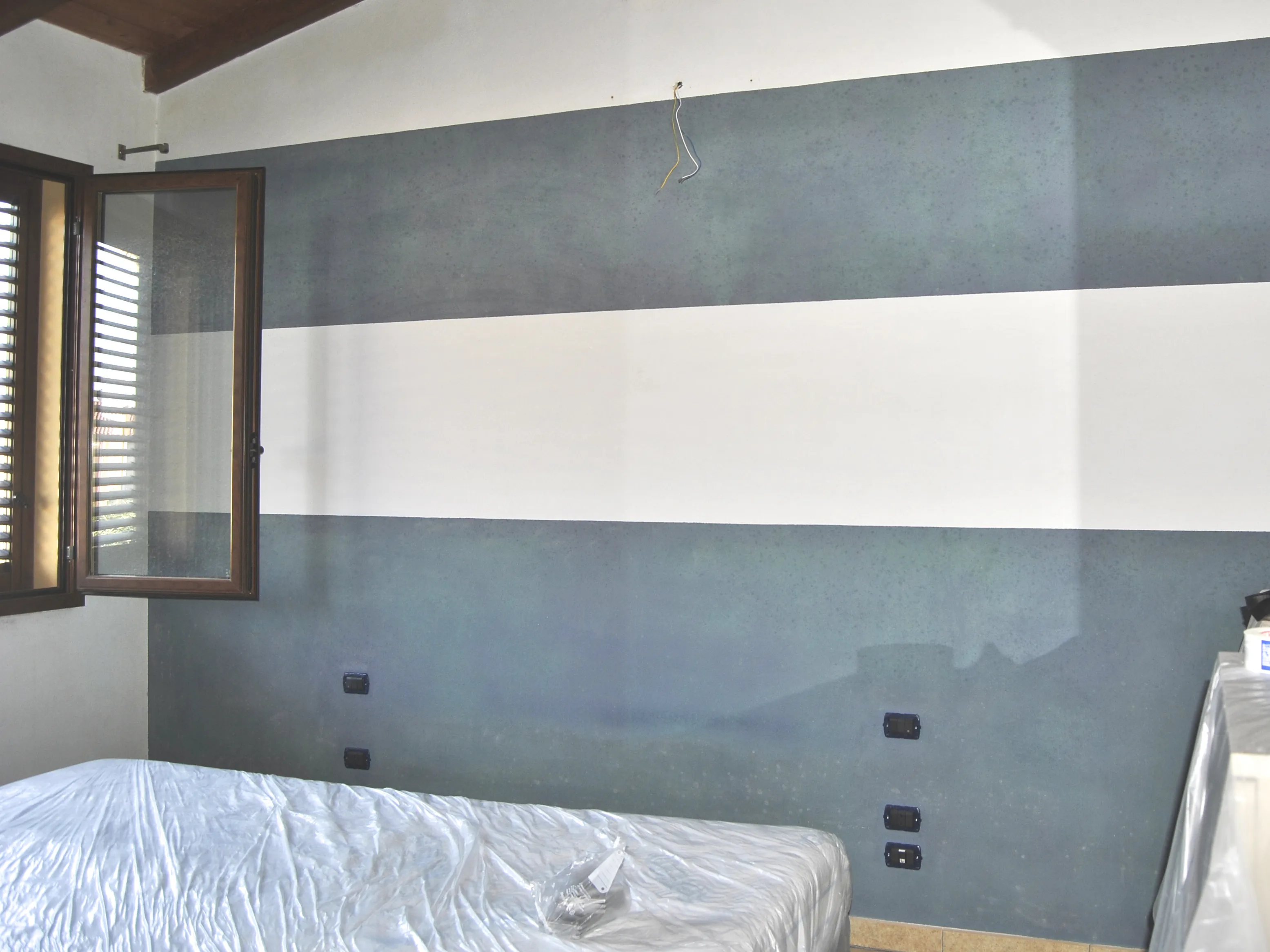 Parete a righe della camera da letto di Metro Room a Monastir, prima dell'intervento